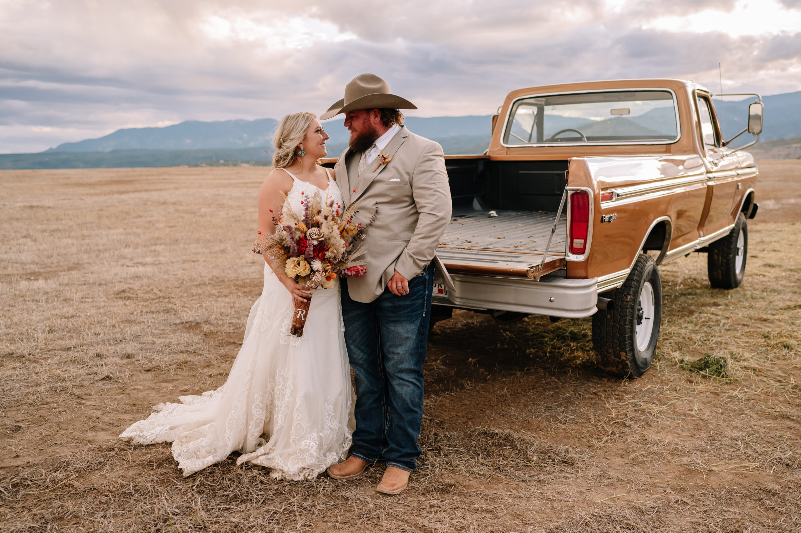 Bride and groom looking into eachother's eyes in front of old Ford pickup truck.